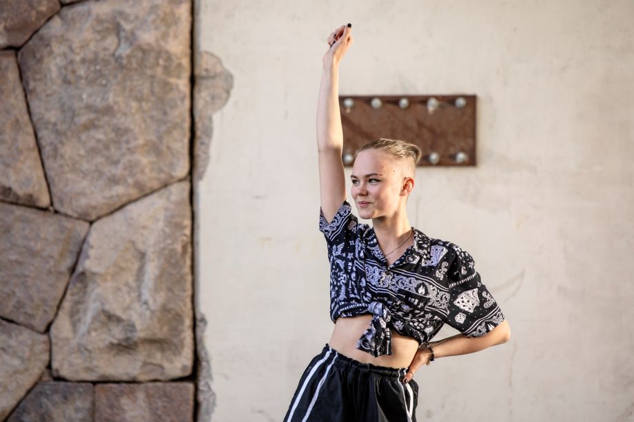 En ungdom ler med handen uppe.