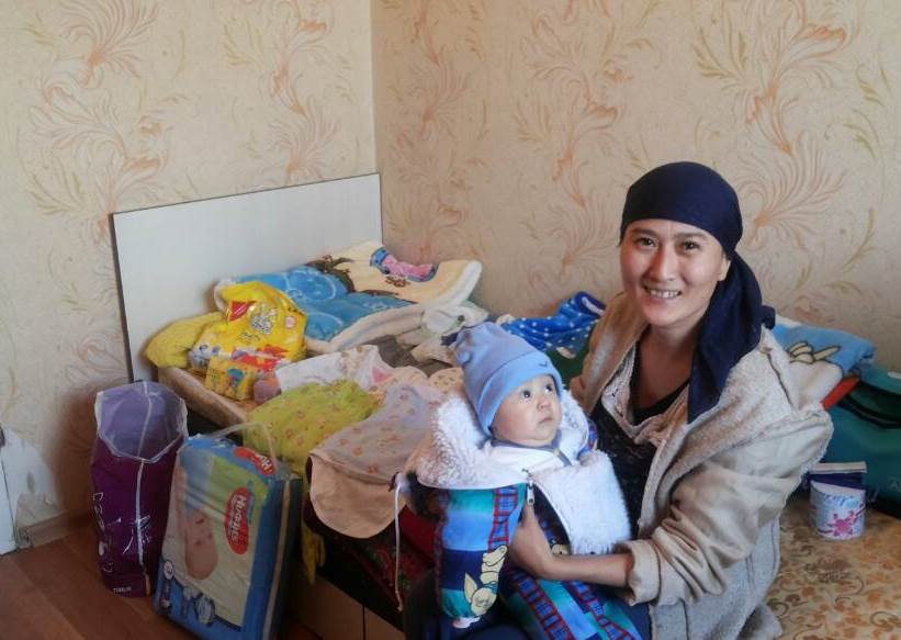 Mother with a baby and the contents of the maternity package.